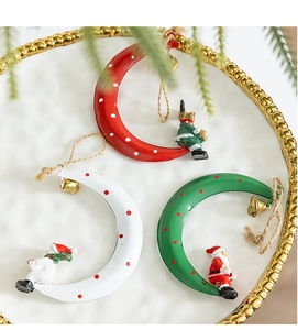 Three metal crescent moon ornaments featuring miniature Santa, elk and snowman with bells