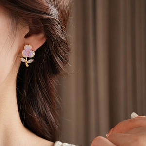 Close-up of elegant purple floral stud earring with gold leaf details on model