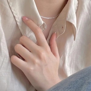 Close-up of minimalist S925 sterling silver chain necklace worn on a silk shirt