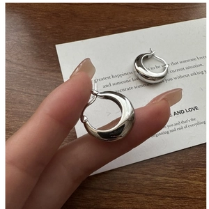 Close-up of S925 sterling silver crescent hoop earrings held to show compact size