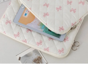 Close-up of white quilted iPad sleeve with pink bow pattern and silver metal zipper