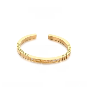 Detail view of gold stainless steel bangle with zircon inlay and etched markings