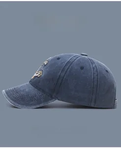 Detailed side view of washed denim baseball cap with tiger embroidery and curved brim
