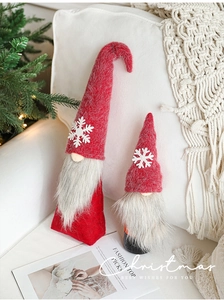 Close-up of plush Swedish Christmas Gnomes with red and grey felt hats on a white sofa