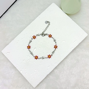 Detail view of 18k gold daisy and star charms on a stainless steel link bracelet