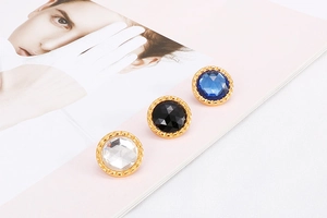 Detail of round crystal stud earrings in white black and blue with gold finish