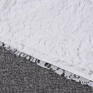 Detailed view of white lace fabric featuring floral embroidery and hollow-out textures