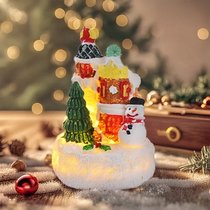 Close-up of LED glowing Christmas miniature scene with snowman and tree in warm light