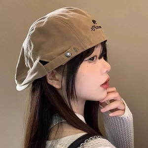 Detailed side view of khaki canvas beret hat with embroidery and metal buckle detail