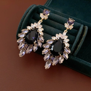 Vue détaillée de boucles d'oreilles en zircon violet en forme de poire sur une boîte chic