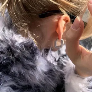 Detail of silver geometric square hoop earring with a stylish braided metal texture
