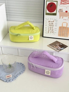 Detail of colorful nylon makeup bags with top handles, dual metal zippers and smile patches