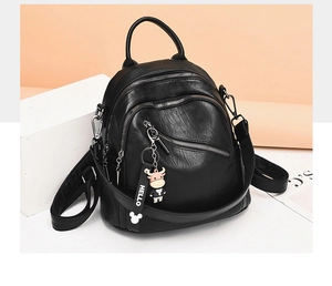 Detail view of black PU leather travel backpack with zipper compartments and cartoon charm