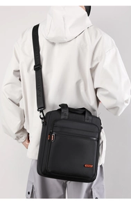 Detail showing the adjustable wide shoulder strap with embossed logo on a black crossbody bag
