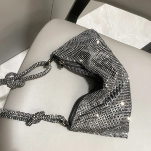 Macro detail of silver rhinestone evening bag showing sparkling crystals and knot strap