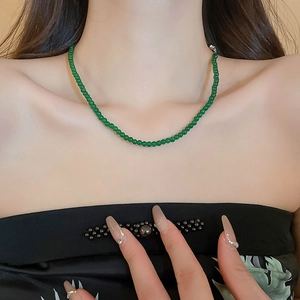 Détail macro du collier de perles en verre vert émeraude porté sur le cou d'un modèle