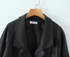 Detail of black faux leather jacket texture and double-breasted V-neck design