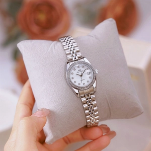 Elegant women's silver watch with rhinestone dial and date display on a grey pillow