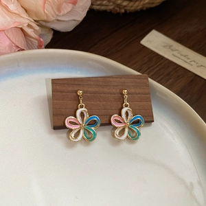 Boucles d'oreilles fleuries multicolores avec base dorée sur un support en bois chic