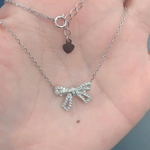 Close-up of S925 sterling silver bow necklace with sparkling crystals held in hand