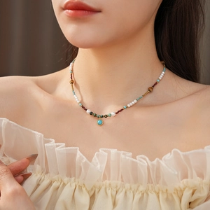 Detail of vintage turquoise pendant and pearl necklace worn on neck over beige clothing