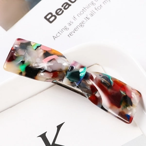 Macro shot of colorful marble pattern acetate hair claw clip with vintage bow design