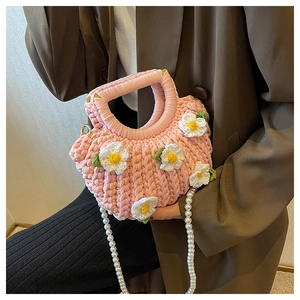 Close-up of pink handmade crochet bag with white daisies and a pearl chain strap