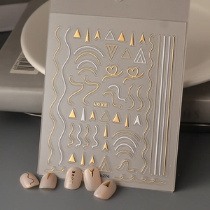 Makroansicht von 3D-Nagelstickern in Gold und Silber mit metallisch geprägter Textur
