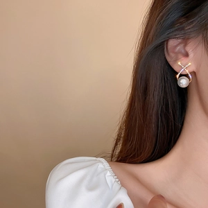 Detailed close-up of a luxury pearl and rhinestone heart earring worn by a model