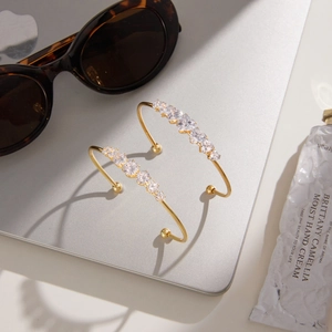 Detail of 18k gold plated stainless steel open bangle with sparkling pear cut zircon stones