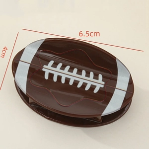 Realistic brown rugby ball hair claw clip with silver stripes and white stitching, 6.5cm
