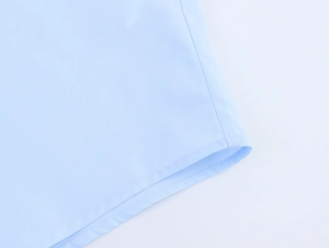 Detailaufnahme des hellblauen Popeline-Stoffs mit präziser Doppelnahtverarbeitung am Saum