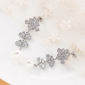 Close-up of fan-shaped silver drop earrings with baguette zircons and white round pearls
