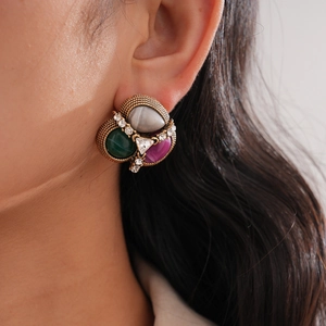 Macro shot of vintage style earrings with grey, green, and red gems on a model ear