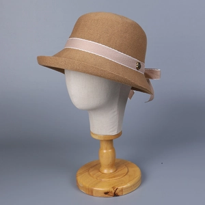 Detail of warm brown knit cloche hat featuring light pink ribbon and vintage gold button