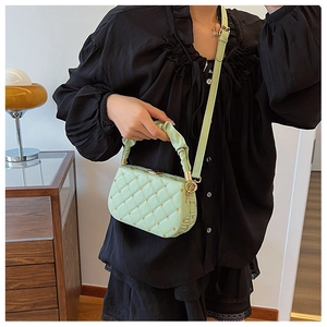 Detail of mint green quilted handbag with gold studs and ruched handle on model