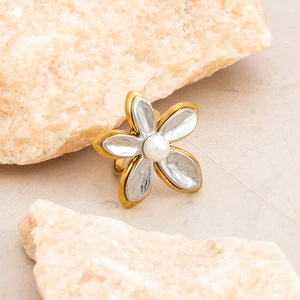 Macro detail of 18K gold plated flower ring with pearl inlay on stone background