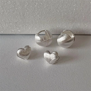 Macro shot of 925 sterling silver brushed heart earrings and spherical studs set