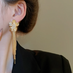Detail of 18k gold plated flower earrings with long metal tassels and white pearl accents