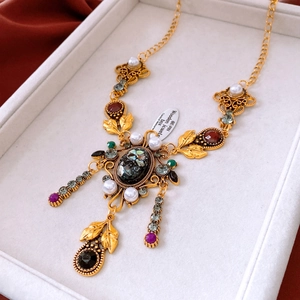 Dettaglio di una collana vintage con gemme colorate e perle su velluto bianco di lusso