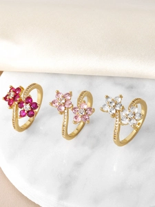 Detailed view of gold flower rings with colorful zircon crystals on marble display