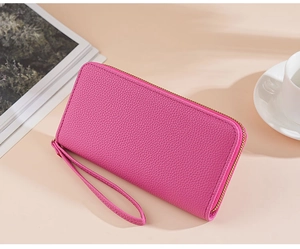 Close-up of pink litchi grain leather long wallet with matching wristlet strap detail