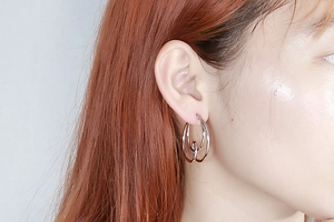 Detailed view of silver minimalist double-interlocking hoop earrings on a model's ear