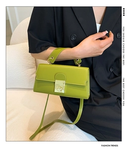 Detail of green faux leather crossbody bag with gold metallic clasp and thin shoulder strap