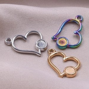 Close-up of heart-shaped metal pendants in silver, gold, and rainbow finishes for DIY jewelry