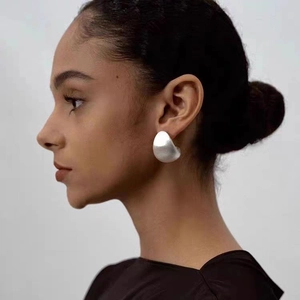 Gros plan sur une boucle d'oreille goutte d'argent avec finition métallique brossée