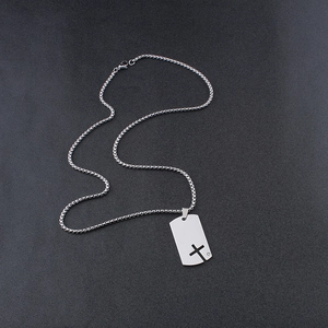 Detail of silver box chain with dog tag pendant featuring a hollow cross and small rhinestone