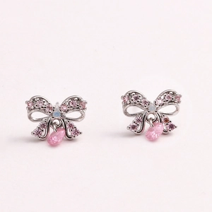 Macro shot of silver bow earrings with pink gemstones and white opals on white background