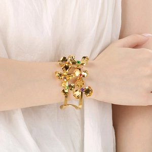 Detail of gold floral cuff bracelet with colorful crystals worn on a model's wrist