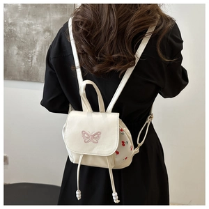 Close-up of white PU leather backpack featuring pink butterfly embroidery and cherry prints